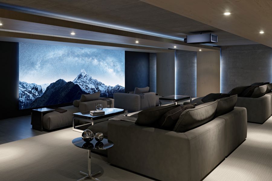 A home theater with chaise lounges, a large screen depicting snow-capped mountains, and a Sony projector.