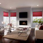 A modern living room with red Serena roller shades by Lutron halfway down the windows.